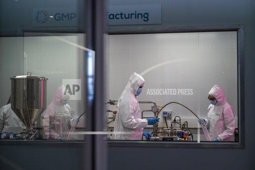 Scientists re-enact the calibration procedure of equipment at an Afrigen Biologics and Vaccines facility in Cape Town, South Africa, Tuesday Oct. 19, 2021. In a pair of warehouses converted into a maze of airlocked sterile rooms, young scientists are assembling and calibrating the equipment needed to reverse engineer a coronavirus vaccine that has yet to reach South Africa and most of the world's poor. (AP Photo/Jerome Delay)