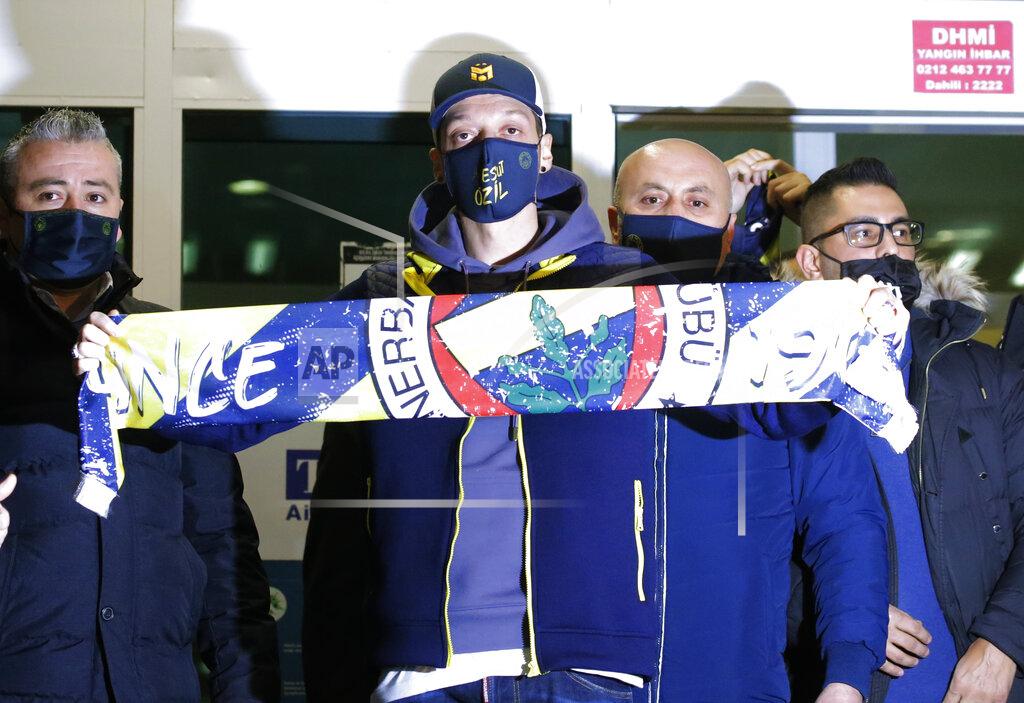 Str Mesut Ozil, former Germany midfielder poses for the photographers with a Fenerbahce scarf after arriving at the Ataturk Airport in Istanbul, early Monday, Jan. 18, 2021. Ozil, who is of Turkish descent, will look to reignite his career in Turkey after he left Arsenal to join Fenerbahce. (AP Photo)
