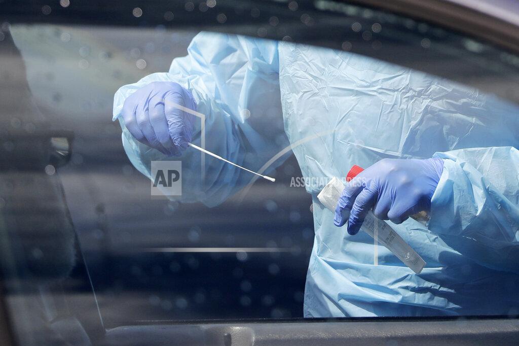 A medical assistant prepares to take a swab from a patient at a new drive-thru and walk-up coronavirus testing site Saturday, April 25, 2020, in Seattle. The site, open Wednesdays and Saturdays from 10 a.m. to 3 p.m. in the Rainier Beach neighborhood, is available to anyone displaying the virus symptoms, are pregnant, over 60 or have a chronic condition, as well as health care workers and first responders. (AP Photo/Elaine Thompson)