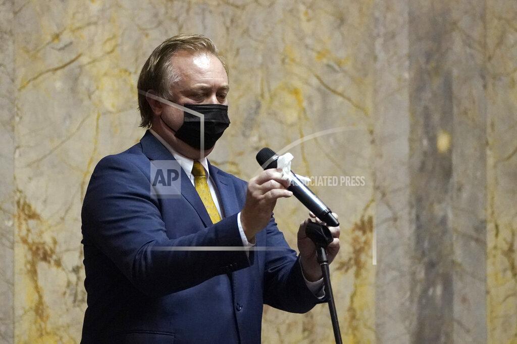 Ted S. Warren FILE - In this Jan. 11, 2021 file photo, Sen. Doug Ericksen, R-Ferndale, wipes off a microphone before speaking on the Senate floor on the first day of the 2021 legislative session at the Capitol in Olympia, Wash. The 2021 session of the Washington Legislature ended Sunday, April 25 and lawmakers had no shortage of weighty topics to consider while having to conduct their work amid a pandemic that meant most meetings and votes were conducted remotely. The Capitol building was also closed to the public since last year due to the COVID-19 pandemic, and was surrounded by security fencing and national guard members at times due to fears of protests. (AP Photo/Ted S. Warren, File)
