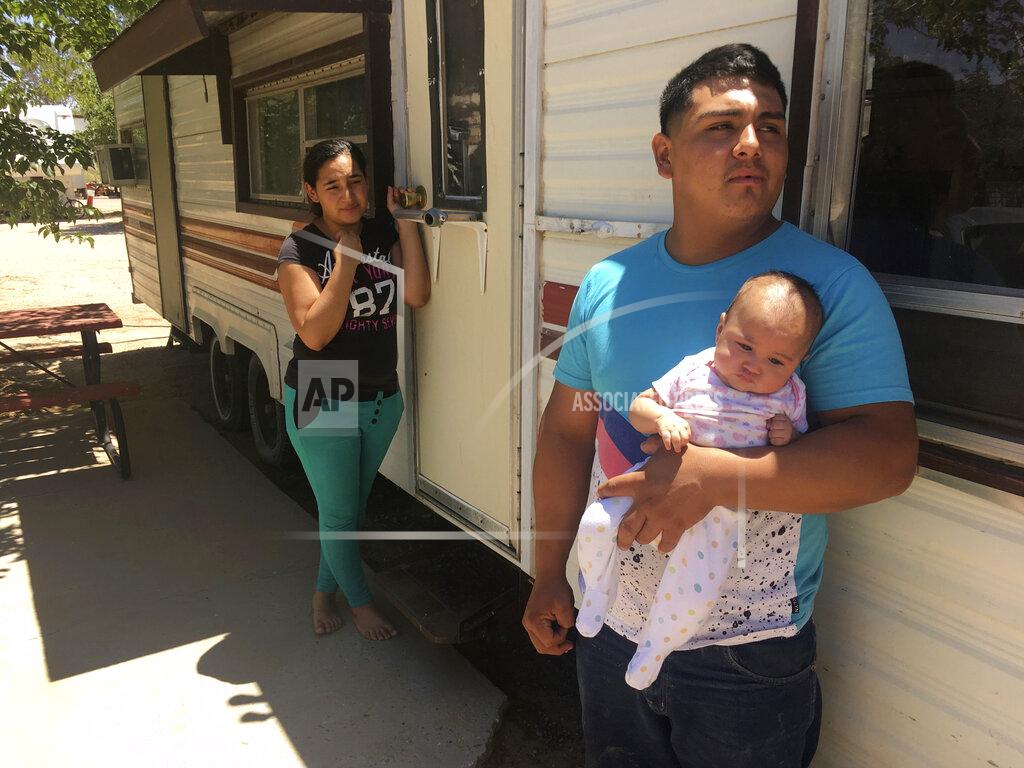 Russell Contreras FILE - In this May 25, 2018, file photo, Jose Espinoza, 18, stands outside his trailer with his 4-month-old infant, Emmily, and wife, Maria Rodriguez, 19, in Vado, N.M. while speaking about making only $50 a day picking onions. New Mexico's child poverty rate rose slightly and continues to rank near the bottom nationally despite improvements in the state's economy, a child-advocacy group said Wednesday, Jan. 15, 2020. The 2019 New Mexico Kids Count Data Book, released by New Mexico Voices for Children, found 26% of the state's children in 2018 remained at or below the federal poverty line. That places the state back to 49th nationally in child poverty. (AP Photo/Russell Contreras, File)