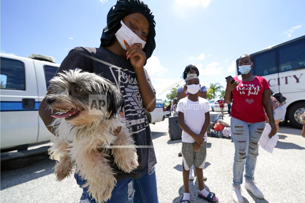 David J. Phillip Tiara Walker holds her dog, Buece, as she waits with her family to board a bus to evacuate Tuesday, Aug. 25, 2020, in Galveston, Texas. The evacuees are being taken to Austin, Texas, as Hurricane Laura heads toward the Gulf Coast. (AP Photo/David J. Phillip)