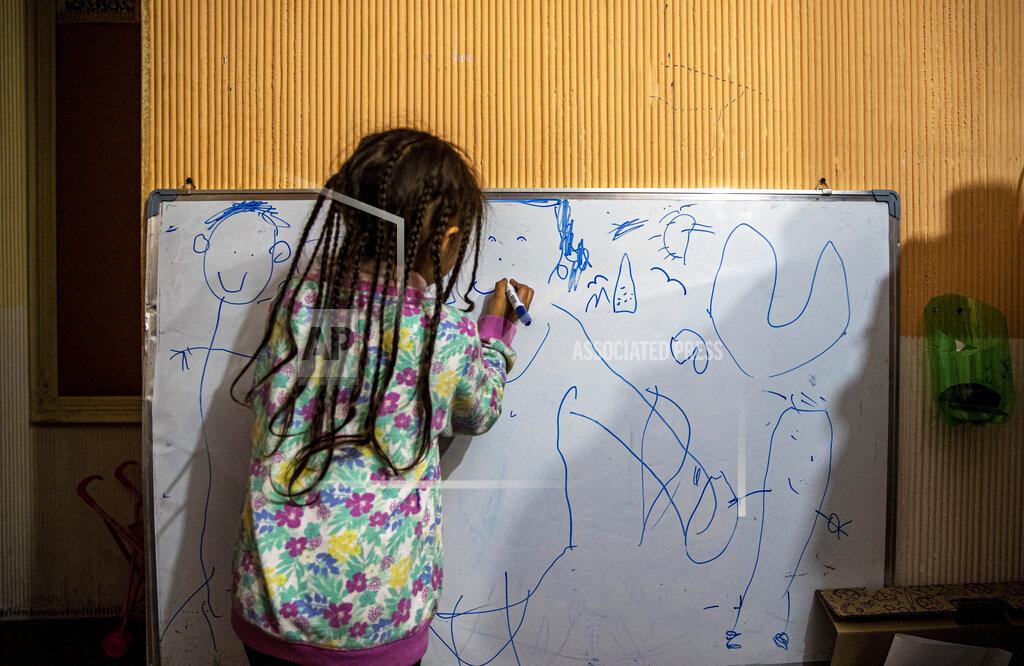 Esteban Felix Kehity Collantes puts a smile on a drawing of her late mother Silvia Cano, who died of COVID-19 at age 37 two months prior, as she illustrates her family, at home where she lives with her father and aunt in Santiago, Chile, Wednesday, Aug. 19, 2020. “Daddy, daddy, why did mommy die?” Kehity asks her father Jose. (AP Photo/Esteban Felix)