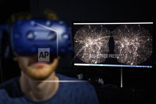 FILE - In this Oct. 12, 2021 file photo, Hadrien Gurnel, software engineer EPFL's Laboratory for Experimental Museology (eM+) explores with a virtual reality helmet the most detailed 3D map of the universe with the virtual reality software VIRUP, Virtual Reality Universe Project developed by Swiss Federal Institute of Technology, in St-Sulpice near Lausanne, Switzerland. The term metaverse seems to be everywhere. Facebook is hiring thousands of engineers in Europe to work on it, while video game companies are outlining their long-term visions for what some consider the next big thing on the internet. Essentially, it’s a world of endless, interconnected virtual communities where people can meet, work and play. You can go to a virtual concert, take a trip online and try on digital clothing. But tech companies still have to figure out how to connect their online platforms.(Laurent Gillieron/Keystone via AP)