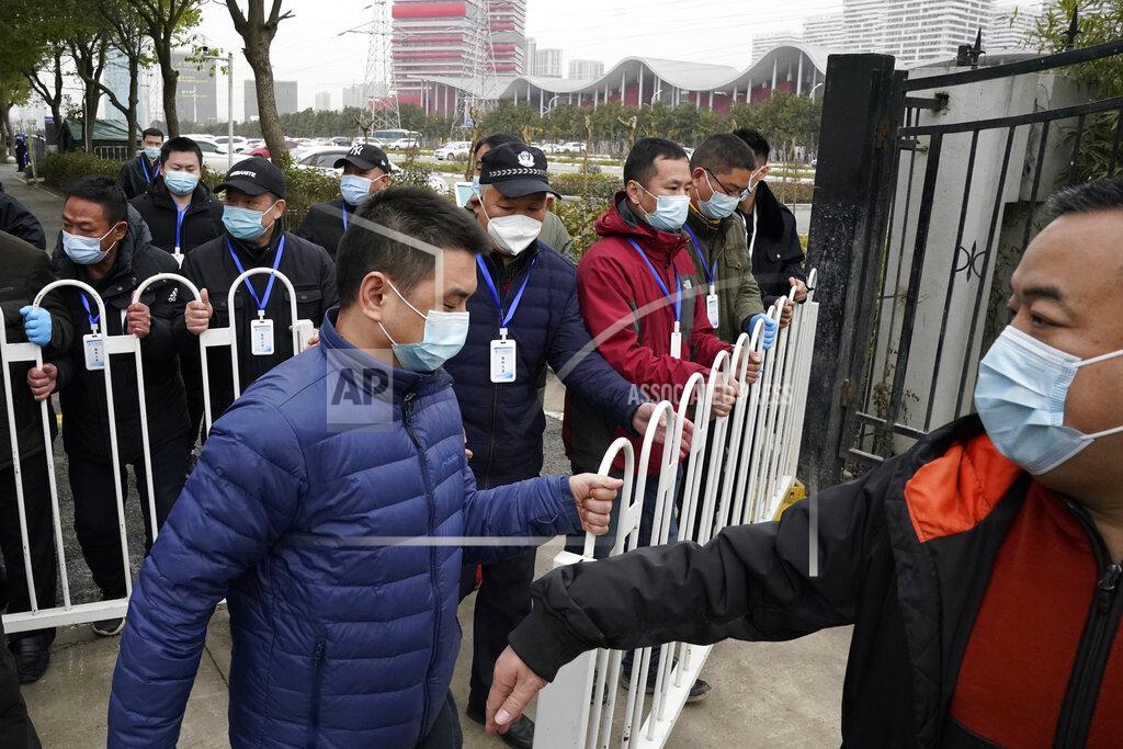 Security personnel move a barrier to clear the way for the World Health Organization team as they depart from the Wuhan Jinyintan Hospital after a field visit in Wuhan in central China's Hubei province on Saturday, Jan. 30, 2021. The World Health Organization team investigating the origins of the coronavirus pandemic visited another Wuhan hospital that had treated early COVID-19 patients on their second full day of work on Saturday. (AP Photo/Ng Han Guan)