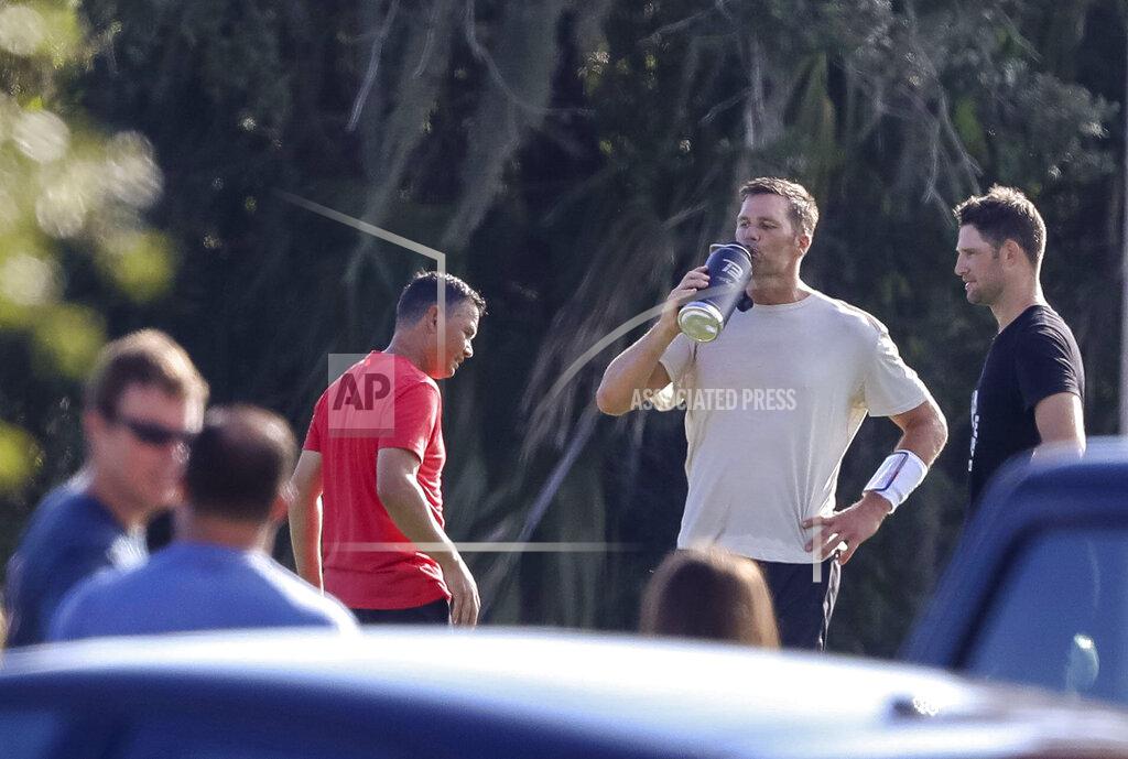 Chris Urso Tampa Bay Buccaneers quarterback Tom Brady takes a drink as unidentified individuals are seen near him during a private workout, Tuesday, June 23, 2020 at Berkeley Preparatory School in Tampa, Fla. (Chris Urso/Tampa Bay Times via AP)