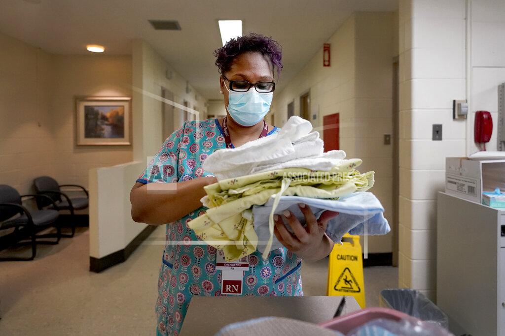 Charles Rex Arbogast Roseland Community Hospital RN Rhonda Jones, prepares bed linens, towels and a hospital gown Friday, Jan. 29, 2021, for a new patient at the South Side of Chicago hospital. Jones has treated many patients with severe COVID-19, a relative died from it, and her mother and a nephew were infected and recovered, but she is still holding out getting the vaccine. (AP Photo/Charles Rex Arbogast)
