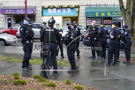 FILE - Seattle Police officers confer after taking part in a public roll call at Hing Hay Park in Seattle's Chinatown-International District Thursday, March 18, 2021. Seattle's police department is having detectives and non-patrol staff respond to emergency calls because of a shortage of officers union leaders fear will be made worse by COVID-19 vaccine mandates. (AP Photo/Ted S. Warren, File)