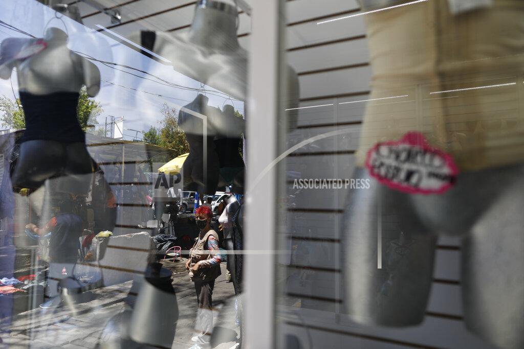 Rebecca Blackwell Rocio, 50, who began sex work for the first time last year after losing her $200/month job as a house cleaner due to the coronavirus pandemic, is reflected in the display window of a lingerie shop in central Mexico City, Thursday, March 25, 2021. Unable to find a new job as a cleaner that paid more than half of her previous one, Rocio decided to try sex work; after an initial spike of interest as a new woman on the street, she found herself still earning far less than her previous salary, and struggling to support her family. (AP Photo/Rebecca Blackwell)
