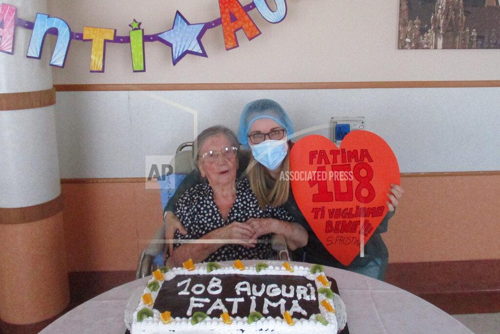 Uncredited In this photo taken on Wednesday, June 3, 2020, Fatima Negrini, left, is flanked by nurse Laura Catena holding a cut out heart reading in Italian " Fatima 108, we love you " while posing in front of a cake celebrating her 108th birthday, at the Anni Azzurri San Faustino nursing home, in Milan, Italy. Fatima Negrini has joined the ranks of the very few centenarians who have recovered from COVID-19. (RSA Anni Azzurri San Faustino via AP)