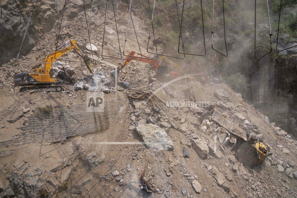 Dar Yasin A damaged truck is covered with rocks and stones as earth movers dig through rubble of a collapsed tunnel in Ramban district, south of Srinagar, Indian controlled Kashmir, Friday, May 20, 2022. An official in Indian-controlled Kashmir said Friday that 10 workers were trapped after part of a road tunnel collapsed in the Himalayan region. (AP Photo/Dar Yasin)