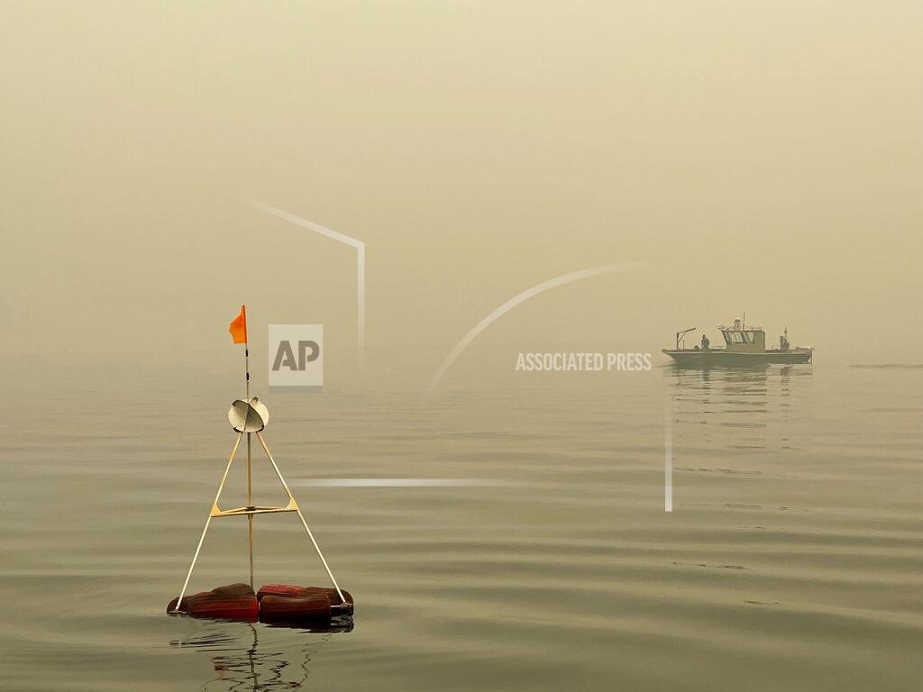 Brandon Berry This photo provided by UC Davis shows a buoy in Lake Tahoe keeps a collection bucket in place that researchers have positioned to measure particles and gauge wildfire's effect on the clarity of Lake Tahoe in Lake Tahoe, Calif., on Aug.23, 2021. Scientists say it's too soon to draw definite conclusions about the lasting damage that record-setting wildfires will have on Lake Tahoe. (Brandon Berry/UC Davis via AP)