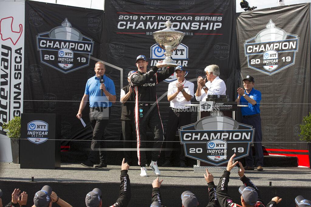 David Royal Josef Newgarden raises the trophy in the air after winning the championship after an IndyCar auto race at Laguna Seca Raceway in Monterey, Calif., Sunday, Sept. 22, 2019. (AP Photo/David Royal)