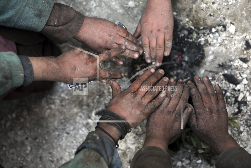 Rahmat Gul Internally displaced boys warm themselves near a fire outside of their temporary home in the city of Kabul, Afghanistan, Wednesday, Dec. 30, 2020. Save the Children has warned that more than 300,000 Afghan children face freezing winter conditions that could lead to illness, in the worst cases death, without proper winter clothing and heating. (AP Photo/Rahmat Gul)