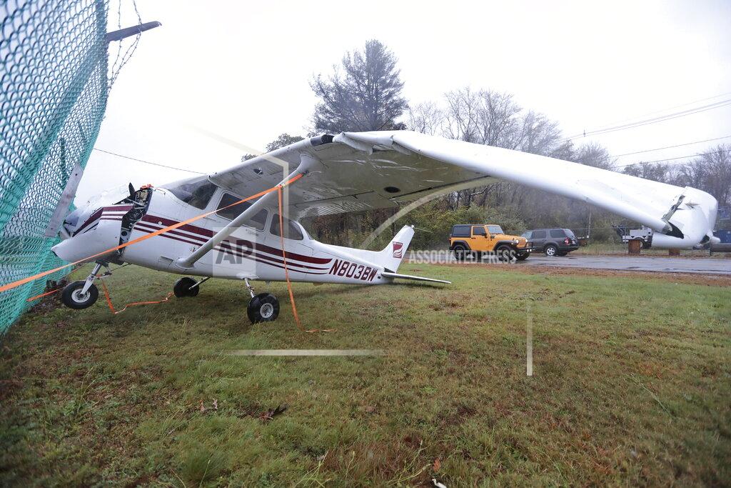 Peter Pereira A small airplane finds itself on the wrong side of the fence, after high winds lifted it over the New Bedford airport fence onto Airport Road on Wednesday, Oct. 27, 2021 as a nor'easter storm slams into the region. (Peter Pereira/The Standard-Times via AP)