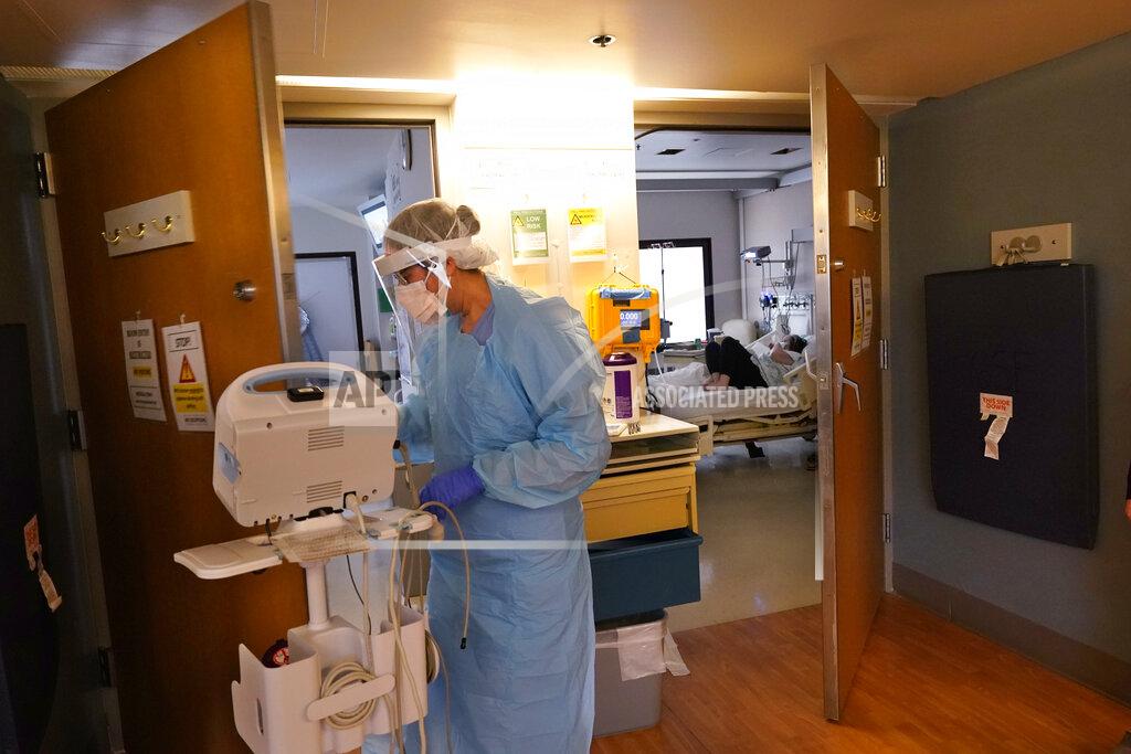 Elaine Thompson Registered nurse Diane Miller moves equipment from a patient's room in the COVID acute care unit at UW Medical Center-Montlake, Tuesday, Jan. 26, 2021, in Seattle. King County, where the hospital is located, has been on a downward trend of COVID-19 cases after two-and-a-half straight months of increases. But the current lull could be, and some experts believe will be, upended as more contagious variants of the virus spread throughout United States. (AP Photo/Elaine Thompson)
