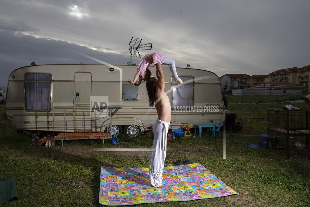 Alessandra Tarantino Alyn Valeriou trains with his 3-year old daughter, Maria Cristina, outside his caravan at the Romina Orfei Circus, parked in San Nicola la Strada, near Naples, Italy, on Sunday April 19, 2020. Anamaria and her husband Alyn Valeriou are thinking to leave the circus to open an educational farm. "But now we are stuck here" said Anamaria. The Orfei itinerant circus made its last performance on March 1, after that show, the national shutdown of public events to contain the spreading of the COVID-19 in Italy blocked 94 animals and nine families. (AP Photo/Alessandra Tarantino)