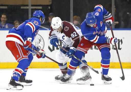New York Rangers defenseman Jacob Trouba (8) and Colorado Avalanche left wing Gabriel Landeskog (92) battle for the puck during the second period of an NHL hockey game, Wednesday, Dec. 8, 2021, in New York. (AP Photo/Noah K. Murray)