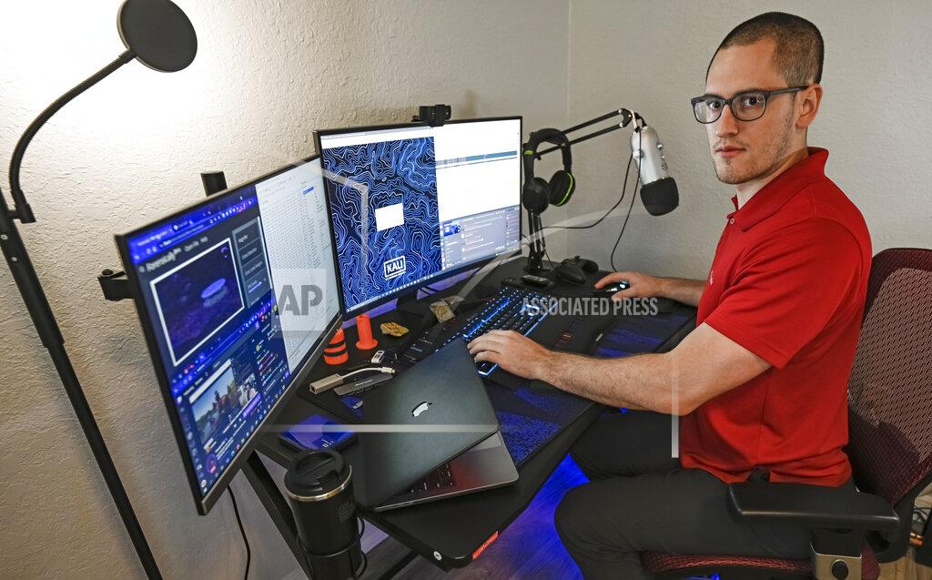 Steve Nesius In this Sept. 20, 2021, photo Austin Moody poses for a photo as he sits a his home work station in Tampa, Fla. Moody, the Michigan native, got a scholarship from the Department of Defense that required working for the agency at least a year after graduating. Moody said he understands that state governments don't have the kind of money that federal agencies or private companies spend on recruiting and generous salaries. (AP Photo/Steve Nesius)