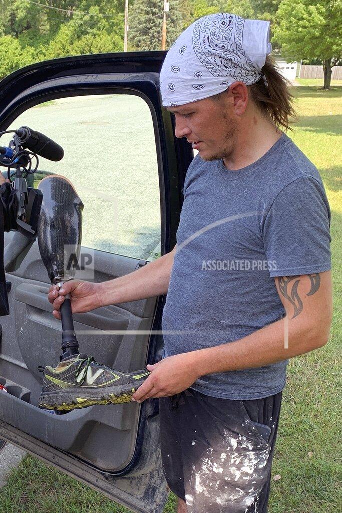 Farmer Joe Marszalkowski holds a prosthetic leg, Monday, July 27, 2020, that he found Sunday in a soybean field on his farm in West Addison, Vt. The leg was lost by double amputee Chris Marckres while skydiving on Saturday. (Jack Thurston/NECN and NBC10 Boston via AP)