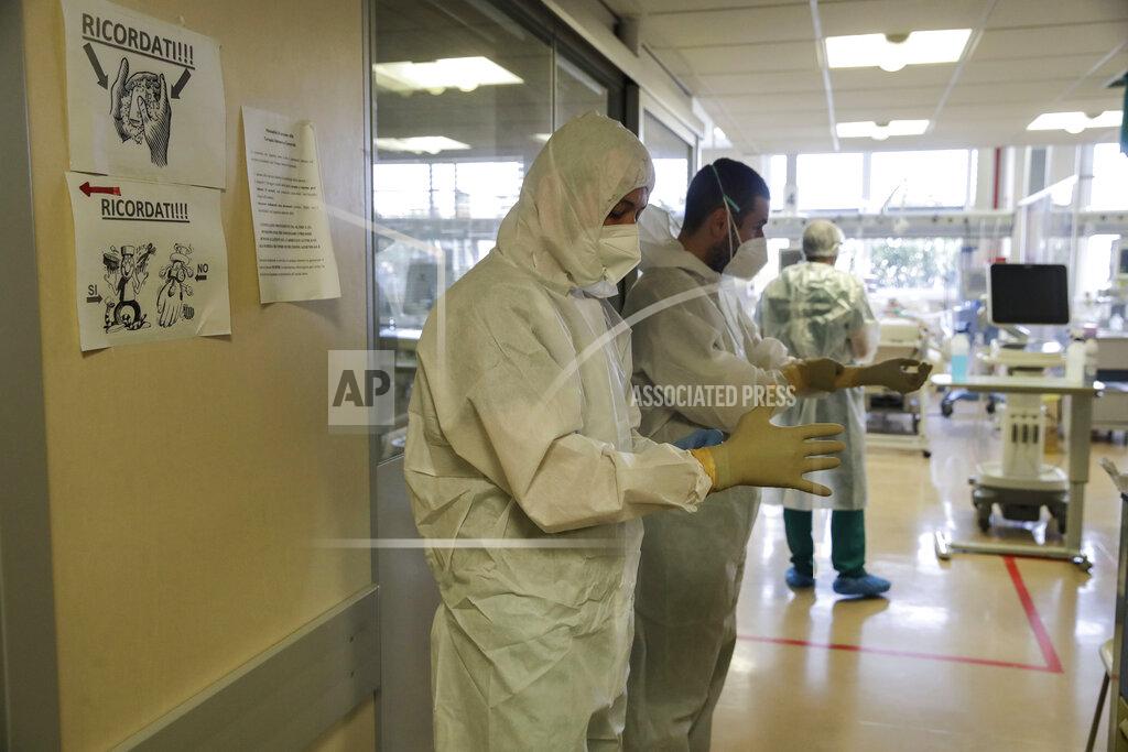 Nurses Simone and his colleague Luciano Ferreri wear their gloves as they prepare to enter the Intensive Care Unit at Varese’s Circolo Hospital, in Varese, Italy, Friday, Nov. 6, 2020. During Italy's autumn pandemic resurgence, concern is falling less on intensive care wards and more on regular medical wards, as eight regions have seen the needle move alarmingly into the red-alert zone with more than half of hospital beds dedicated to coronavirus patients. (AP Photo/Luca Bruno)