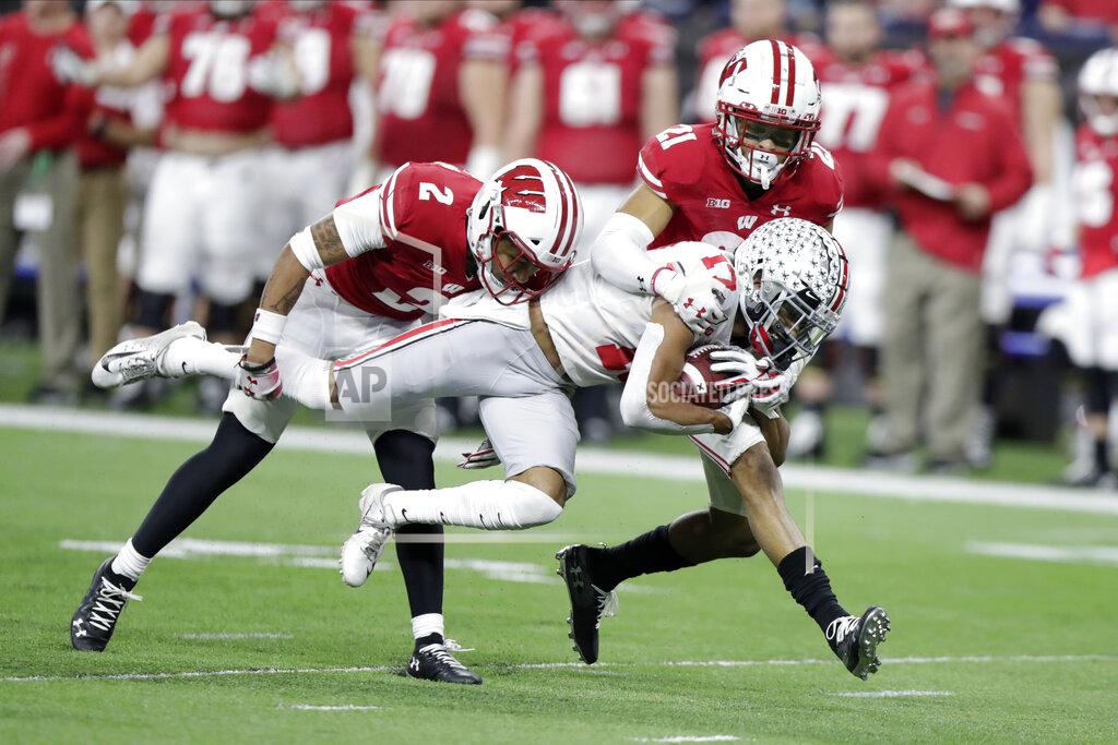 Michael Conroy Ohio State wide receiver Chris Olave (17) is tackled by Wisconsin safety Reggie Pearson (2) and cornerback Caesar Williams (21) during the second half of the Big Ten championship NCAA college football game Saturday, Dec. 7, 2019, in Indianapolis. (AP Photo/Michael Conroy)