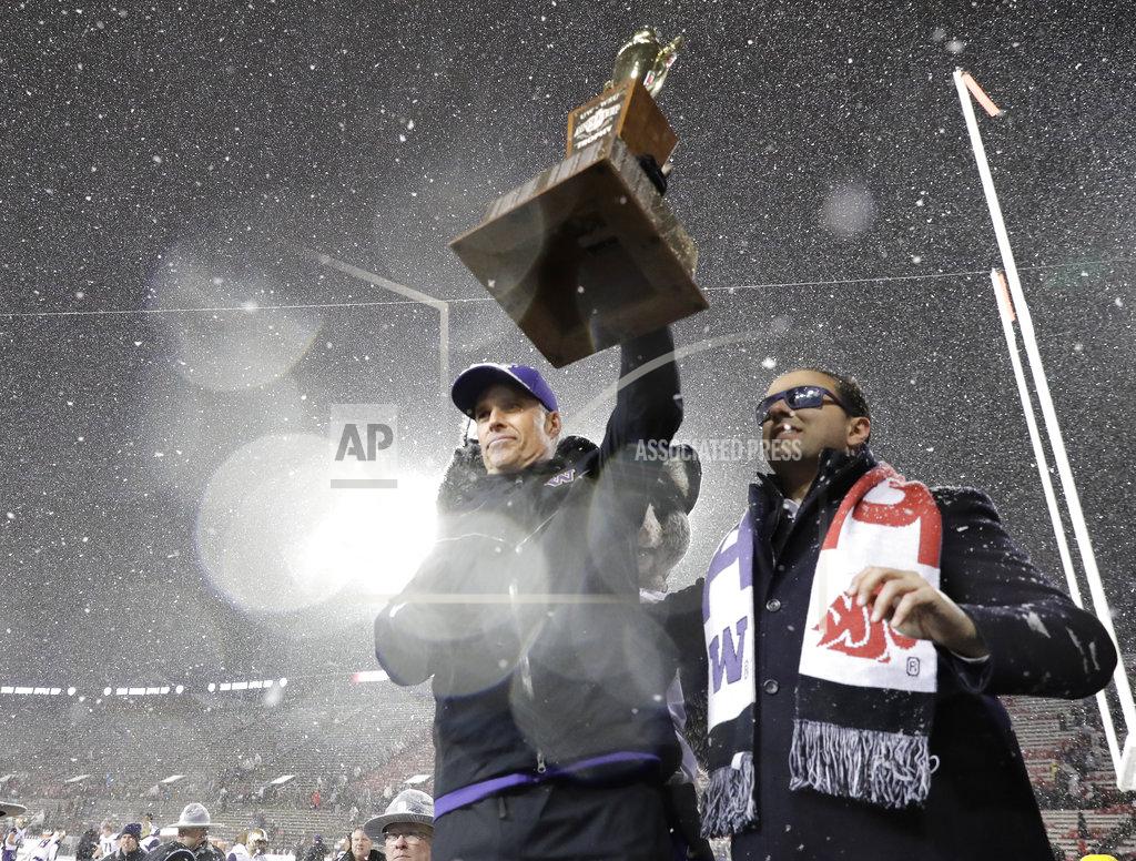 Ted S. Warren Washington head coach Chris Petersen, left, holds the Apple Cup trophy after it was presented to him by Washington Lt. Gov. Cyrus Habib, right, after Washington defeated Washington State 28-15 in an NCAA college football game, Friday, Nov. 23, 2018, in Pullman, Wash. (AP Photo/Ted S. Warren)
