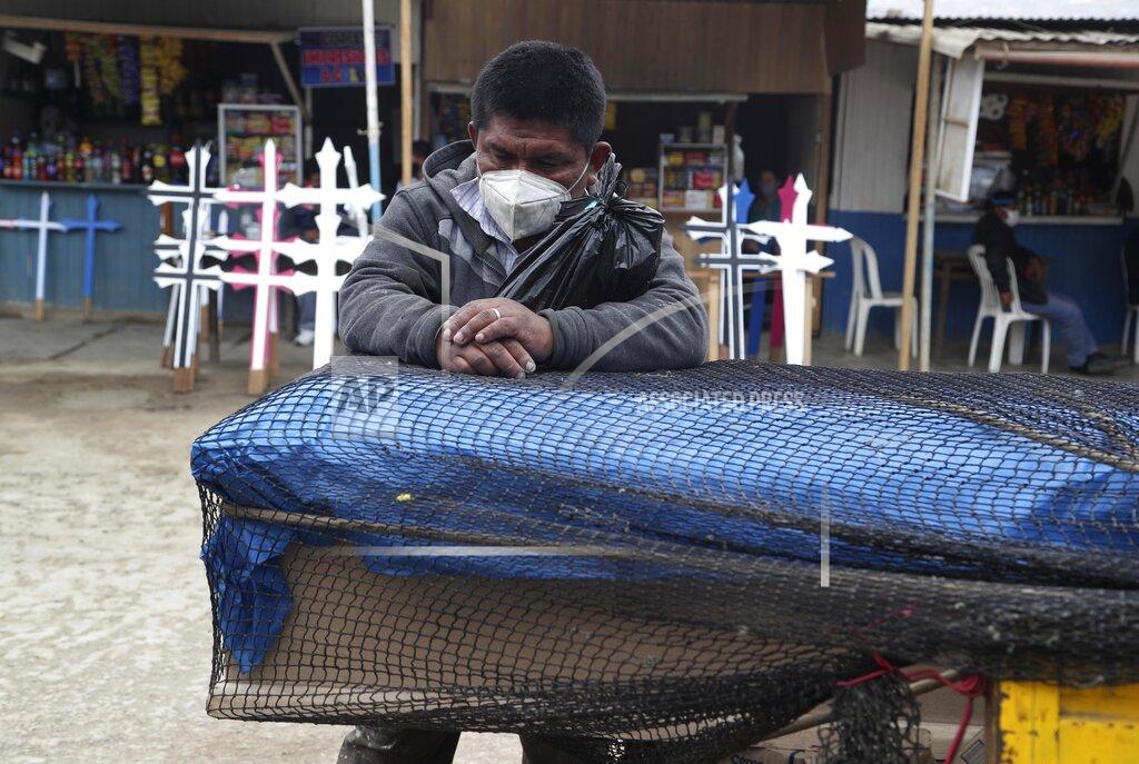 Martin Mejia Robert Liza stands over the coffin of his father Martin Liza, who he said died Tuesday of complications related to COVID-19, outside the Nueva Esperanza cemetery on the outskirts of Lima, Peru, Friday, Aug. 28, 2020. Liza said he doesn't have the money to bury his 70-year-old father, and that he and his brother have slept for two nights alongside the coffin outside the cemetery in hopes the cemetery will let them bury their father for free. (AP Photo/Martin Mejia)