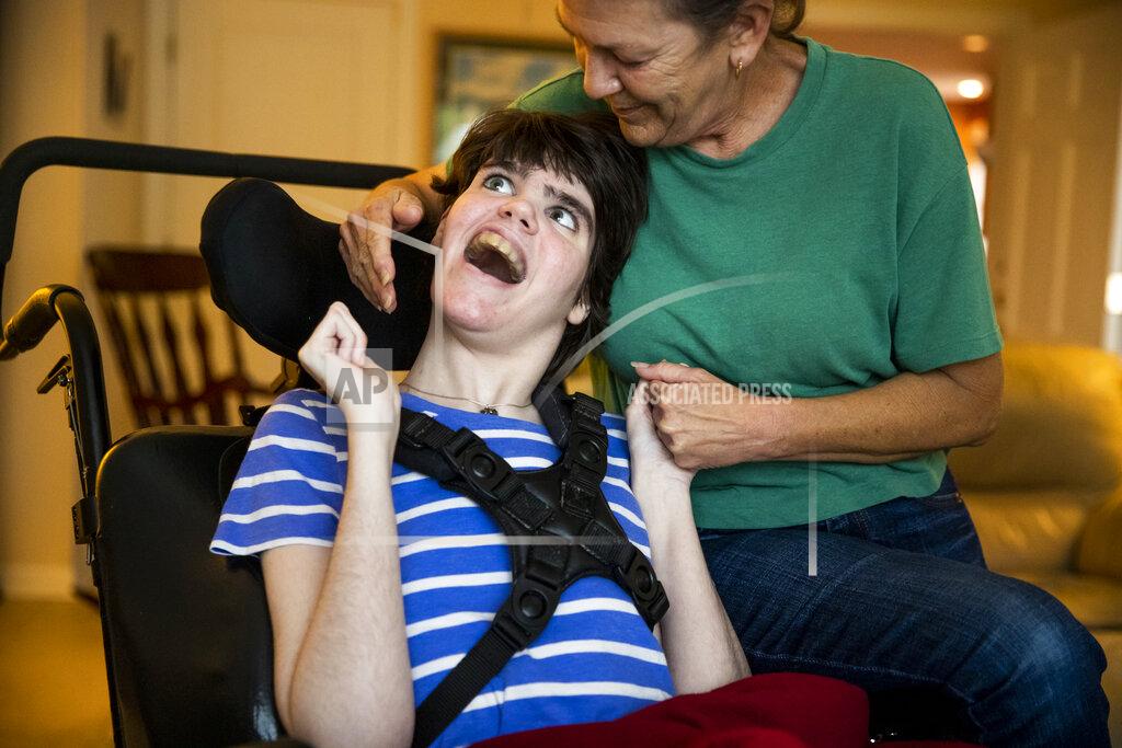 Sophia Germer Sue Roesky kisses her daughter Lauren who has cerebral palsy and is non-verbal, at their home in Metairie, La., Friday, Sept. 17, 2021. (Sophia Germer/The Times-Picayune/The New Orleans Advocate via AP)