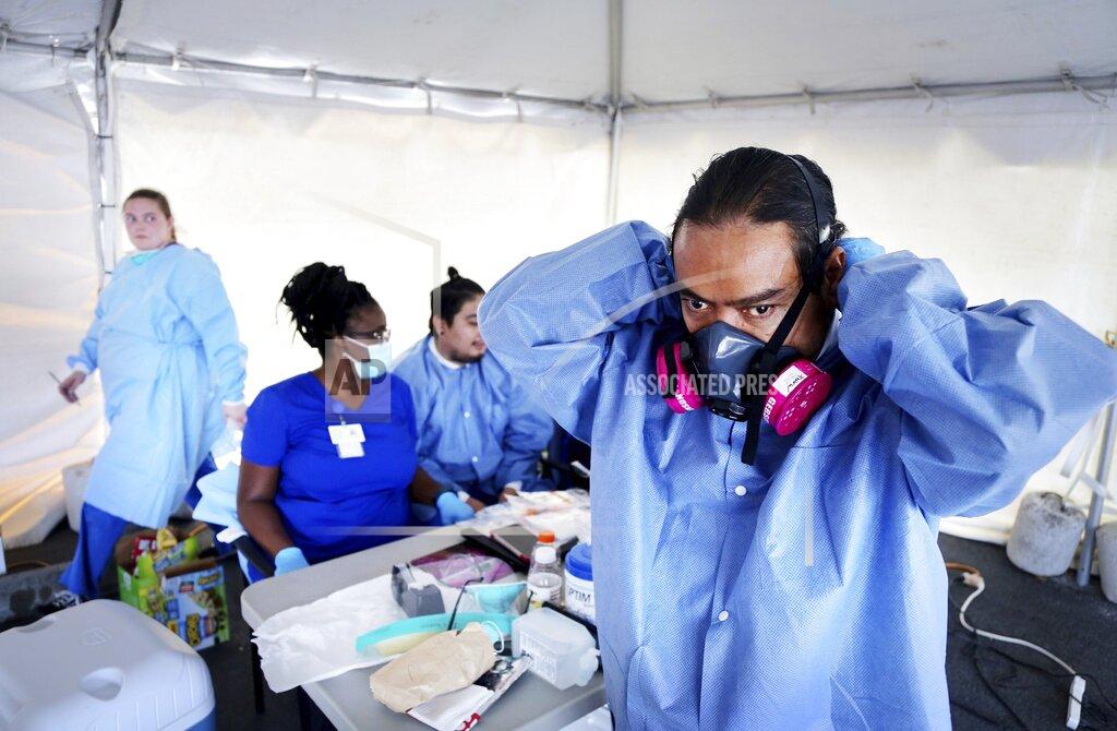 Douglas R. Clifford Mark Thompson, of Clearwater, dons a variety of PPE, including a respirator mask, before administering a COVID-19 viral test on Wednesday, May 6, 2020, at Community Health Centers of Pinellas, in Clearwater where Pinellas County began COVID-19 testing on Monday.(Douglas R. Clifford/Tampa Bay Times via AP)