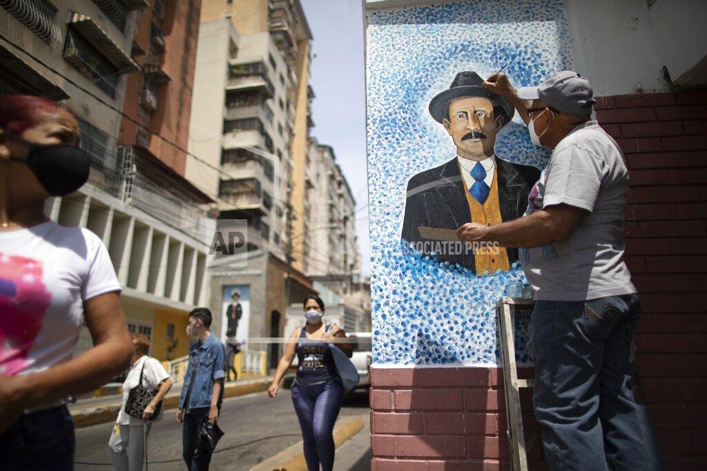 Ariana Cubillos Venezuelan artist Mervin Marmol puts finishing touches on his painting of late Venezuelan Dr. Jose Gregorio Hernandez at the street corner where he died in a car accident in 1919 in La Pastora neighborhood in Caracas, Venezuela, Monday, April 26, 2021. Known as the "doctor of the poor, Hernandez is set to be beatified by the Catholic church, a step towards sainthood, on April 30th. (AP Photo/Ariana Cubillos)
