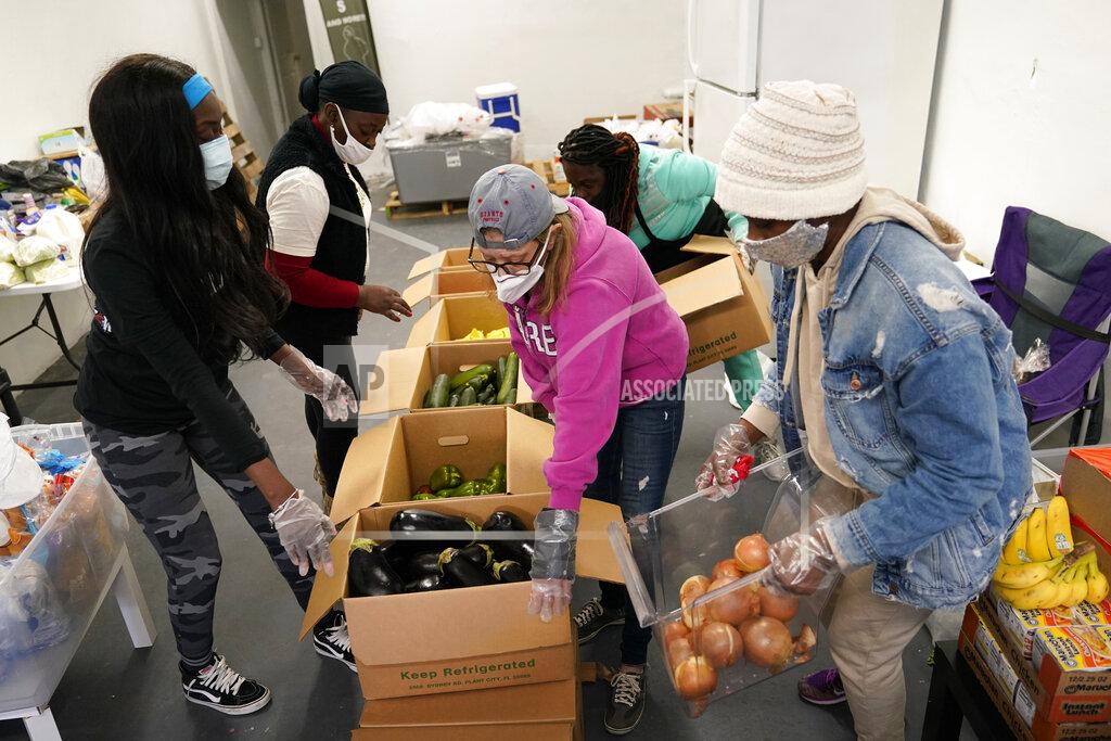 Lynne Sladky Sherina Jones, left, works with volunteers organizing food for distribution, Wednesday, Dec. 9, 2020, in the Liberty City neighborhood of Miami. Jones offers free food for the community from a stocked community refrigerator called the Village Freedge. When one of the refrigerators was stolen just before Thanksgiving, the community and friends came together to help to purchase a new one. Jones also provides hot food and distributes numerous food pantry items. She has applied for non-profit status and is transitioning to become a food bank. (AP Photo/Lynne Sladky)