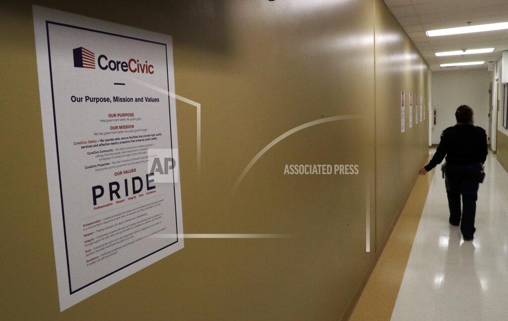 Gregory Bull A guard passes a sign for CoreCivic at the Otay Mesa Detention Center Wednesday, Aug. 23, 2017, in San Diego. The facility was at the center of the first big novel coronavirus outbreak at a U.S. immigration detention center in April 2020. (AP Photo/Gregory Bull)