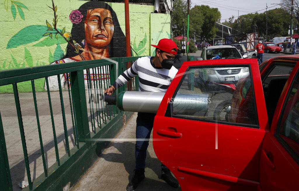Marco Ugarte A person loads into the back seat of a car a tank filled with oxygen for a family member sick with COVID-19, in the Iztapalapa borough of Mexico City, Friday, Jan. 15, 2021. The city offers free oxygen refills for COVID-19 patients. (AP Photo/Marco Ugarte)