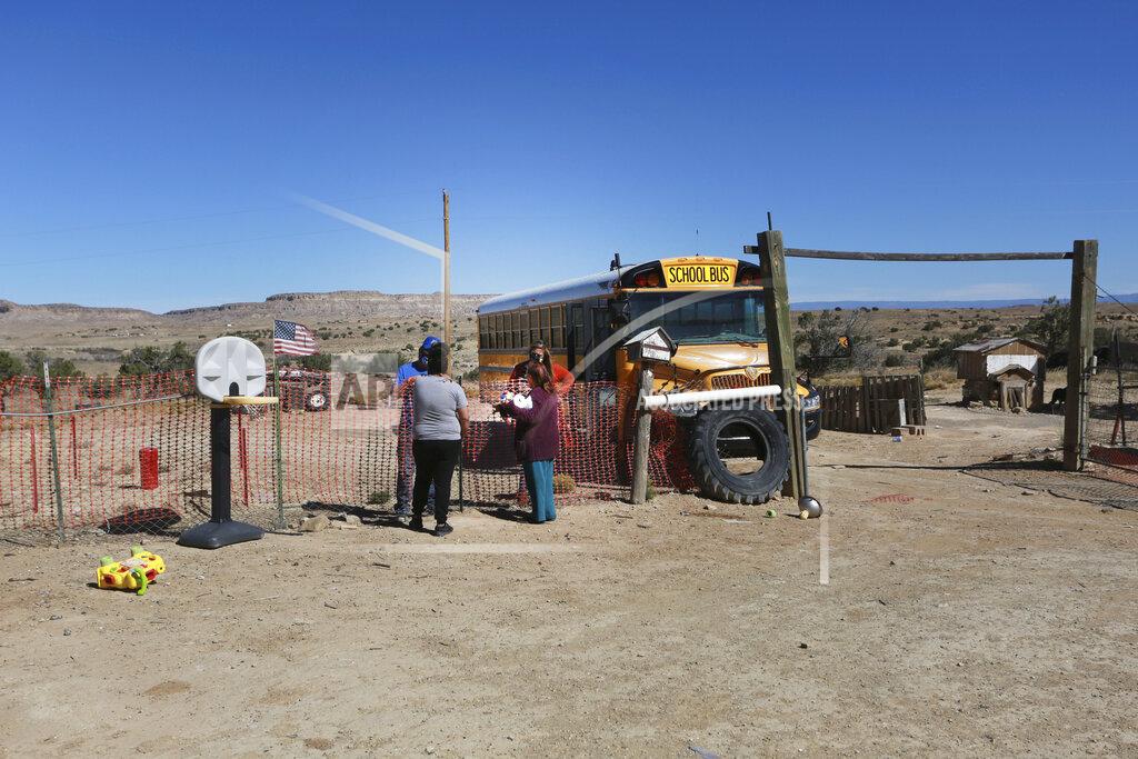 Cedar Attanasio Social worker Victoria Dominguez, background right, delivers supplies she collected at Cuba High School, to deliver along a rural school bus route outside Cuba, N.M., Oct. 19, 2020. The switch to remote learning in rural New Mexico has left some students profoundly isolated — cut off from others and the grid by sheer distance. The school system is sending school buses to students’ far-flung homes to bring them assignments, meals and a little human contact. (AP Photo/Cedar Attanasio)