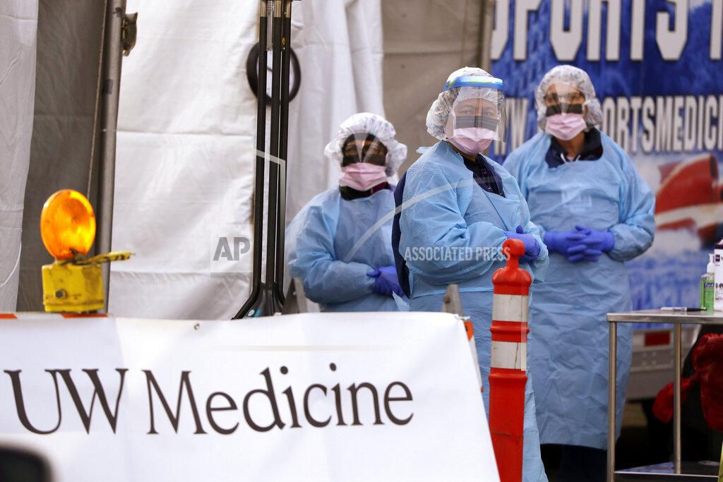 FILE - In this March 17, 2020, file photo, medical personnel wait for a driver to pull up at a drive-thru COVID-19 testing station for University of Washington Medicine patients in Seattle. Experts and health officials who are trying to plan a response to the coronavirus outbreak are missing a critical piece of information – the number of health care workers who have tested positive for the disease. (AP Photo/Elaine Thompson, File)