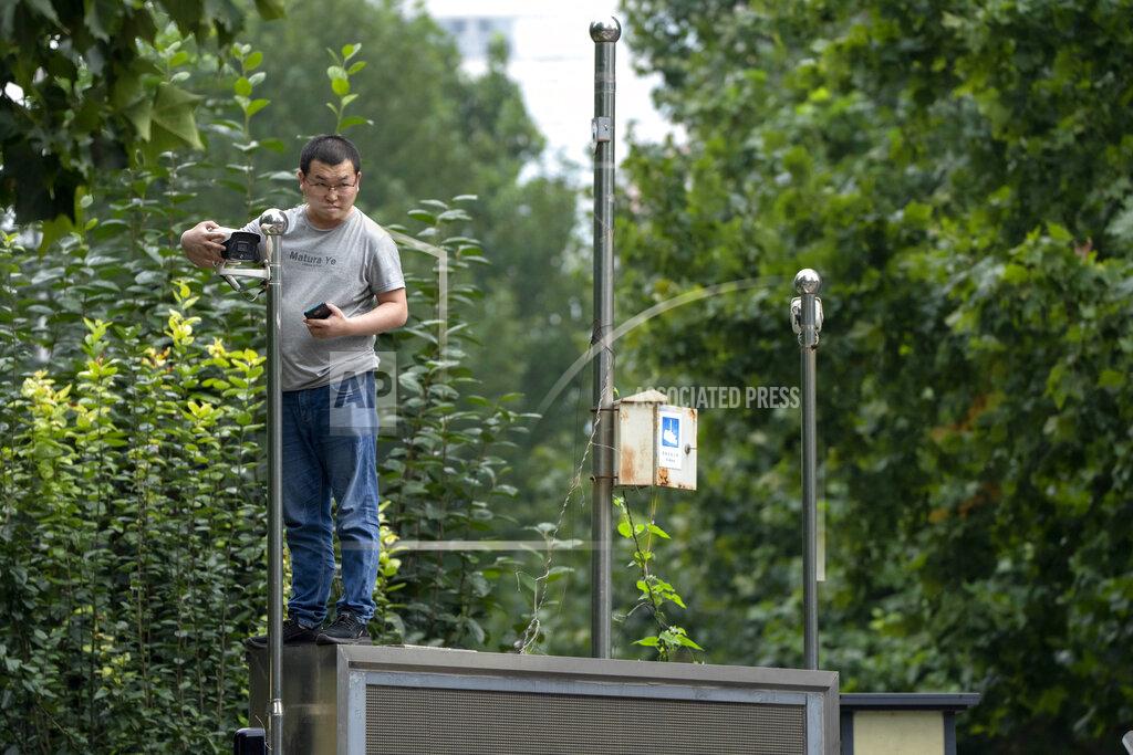 Mark Schiefelbein A man stands on an electronic signboard as he adjusts a security camera at a courthouse in Beijing, Tuesday, Sept. 14, 2021. A young Chinese woman headed to court Tuesday amid a police cordon and antagonistic bystanders in one of the few remaining MeToo cases from a tamped-down movement whose legacy remains uncertain. (AP Photo/Mark Schiefelbein)