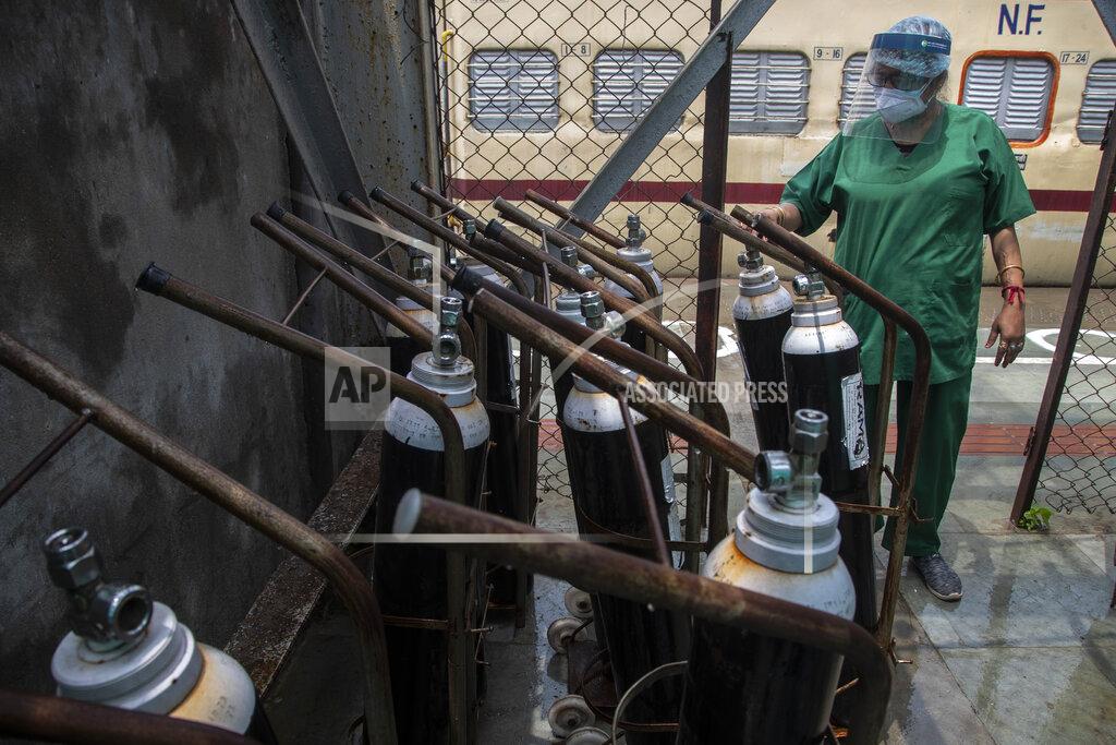 A health worker checks oxygen cylinders stored next to a train prepared as COVID-19 care centre in the wake of spike in the number of positive coronavirus cases, at a railway station in Gauhati, India, Thursday, May 6, 2021. Infections in India hit another grim daily record on Thursday as demand for medical oxygen jumped seven-fold and the government denied reports that it was slow in distributing life-saving supplies from abroad. (AP Photo/Anupam Nath)