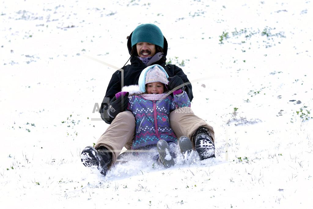 David J. Phillip Robert Savannah and his daughter Sophia, 4, slide down a snow covered hill Monday, Feb. 15, 2021, in Houston. A winter storm dropping snow and ice sent temperatures plunging across the southern Plains, prompting a power emergency in Texas a day after conditions canceled flights and impacted traffic across large swaths of the U.S. (AP Photo/David J. Phillip)