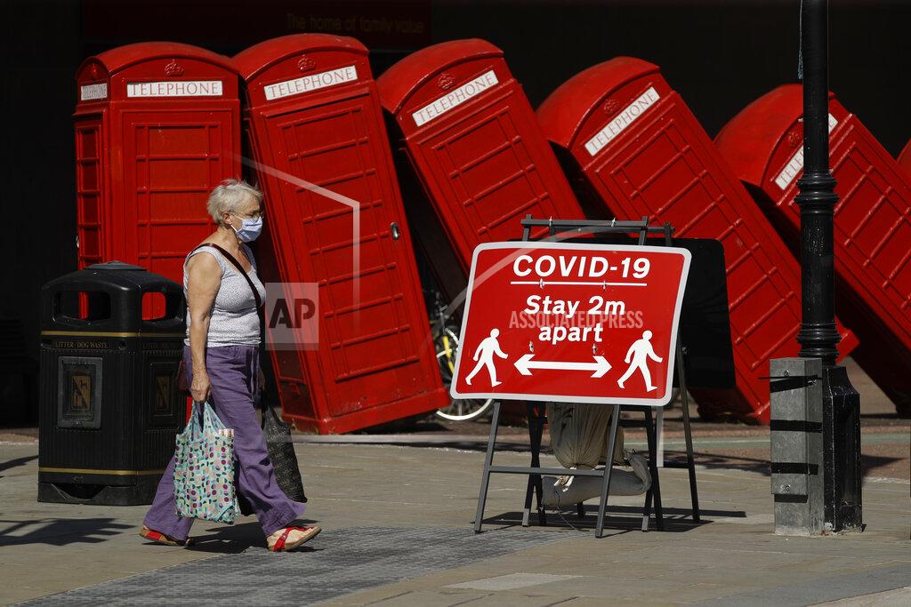 A sign requesting people stay two meters apart to try to reduce the spread of COVID-19 is displayed in front of "Out of Order," a 1989 sclupture made of red telephone boxes by British artist David Mach, in Kingston upon Thames, southwest London, Monday, June 22, 2020. (AP Photo/Matt Dunham)