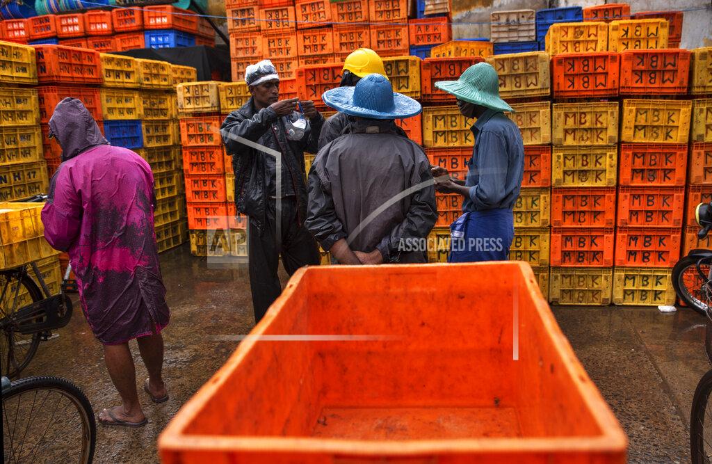 R S Iyer A man prepares to wear his mask as fish vendors chat on a rainy day in Kochi, Kerala state, India, Monday, June 22 2020. India is the fourth hardest-hit country by the COVID-19 pandemic in the world after the U.S., Russia and Brazil. (AP Photo/R S Iyer)