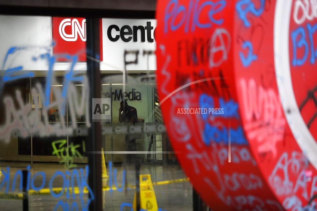 Brynn Anderson A security guard walks behind damaged glass at the CNN Center building in the aftermath of a demonstration against police violence on Saturday, May 30, 2020, in Atlanta. (AP Photo/Brynn Anderson)