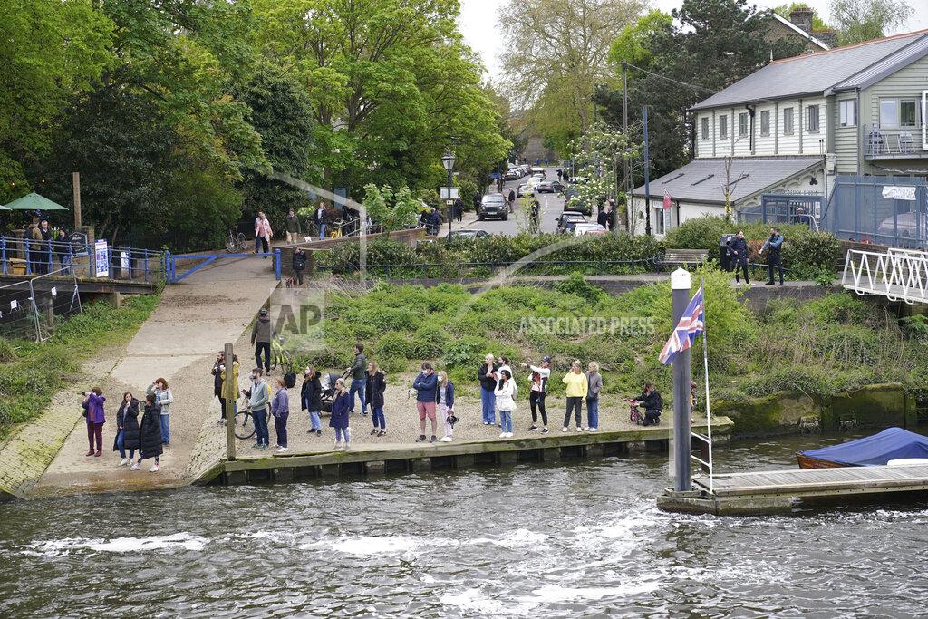 Yui Mok People gather at Teddington Lock to try and spot a Minke whale, which was freed on Sunday after it became stuck on Richmond lock's boat rollers but has remained in the Thames, is seen near Teddington Lock in London, Monday, May 10, 2021. A Port of London Authority spokesperson said a whale had never been seen this far up the Thames before, some 95 miles from its mouth. (Yui Mok/PA via AP)
