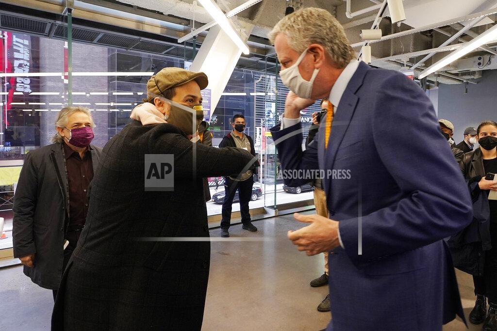 Richard Drew Actor Lin-Manuel Miranda, center, and New York Mayor Bill de Blasio, bump elbows before they tour the grand opening of a Broadway COVID-19 vaccination site intended to jump-start the city's entertainment industry, in New York, Monday, April 12, 2021. At left is Miranda's father. Luis A. Miranda, Jr. (AP Photo/Richard Drew, Pool)