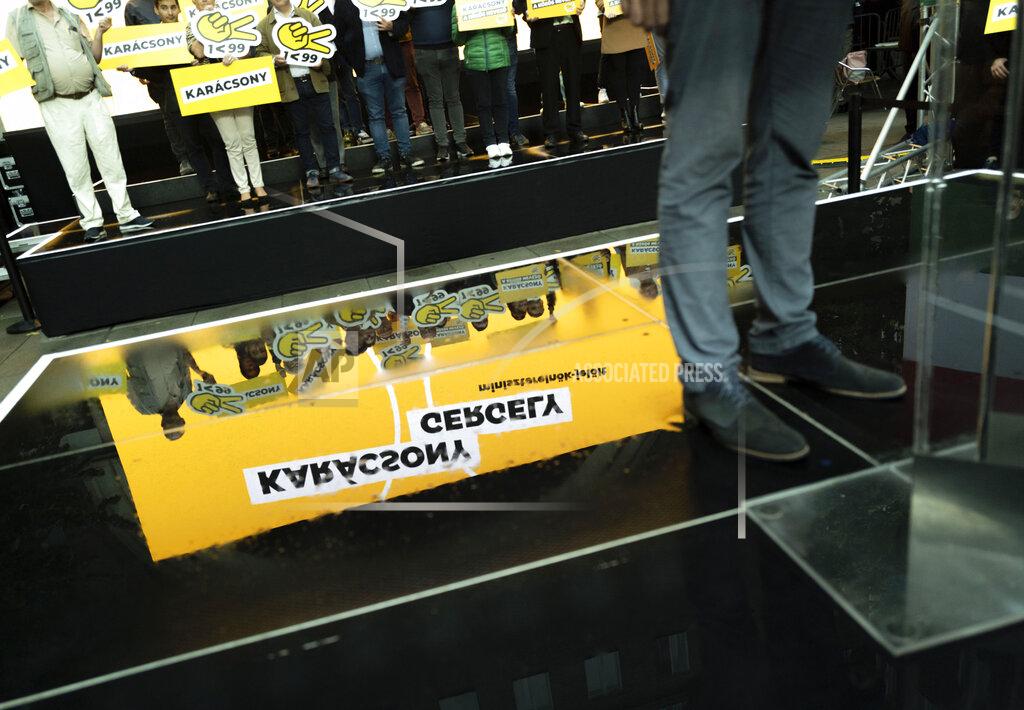 Bela Szandelszky A campaign banner is seen reflected behind Budapest mayor Gergely Karacsony, one of the frontrunners in a race to unseat Hungary's Prime Minister Viktor Orban, while holding a campaign event in Budapestt, Hungary on Sept. 17, 2021. The rally marked the start of a primary election that will choose a joint opposition candidate to face off with Hungary's hardline leader in polls next year. (AP Photo/Bela Szandelszky)