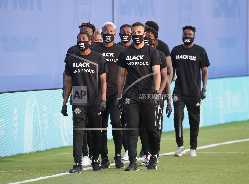 John Raoux Members of all the MLS soccer teams march around the stadium before a soccer match Wednesday, July 8, 2020, in Kissimmee, Fla., wearing shirts and masks with messages about race. (AP Photo/John Raoux)