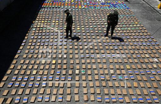 FILE - In this Thursday, Aug. 10, 2017 file photo, police officers walk among packages of seized cocaine at the Pacific port of Buenaventura, Colombia, after about one ton of cocaine was seized in a container during an operation by counternarcotics police at the port. In 2018, Capt. Juan Pablo Mosquera, a Colombian national police officer who was part of an elite unit that worked closely with U.S. anti-narcotics agents, was extradited to Miami to stand trial on charges he betrayed the U.S. Drug Enforcement Administration to the same traffickers they were jointly fighting. (AP Photo/Fernando Vergara)