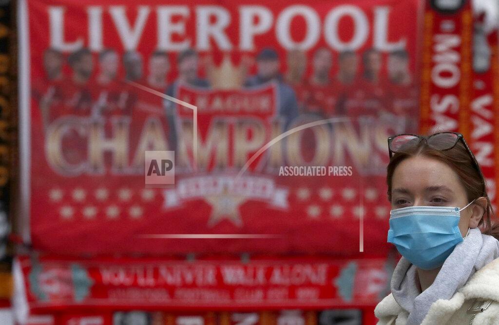Frank Augstein A woman wearing a face-covering walks past Liverpool soccer club merchandise on sale in Liverpool, England, Wednesday, Oct. 14, 2020. Scarred by abandoned buildings and government neglect during the 1980s, Liverpool made itself vibrant again by promoting local culture, nightlife, soccer and ties to the Fab Four. However, Liverpudlians retained their mistrust of London politicians, and the virus pandemic has brought it to the surface. (AP Photo/Frank Augstein)