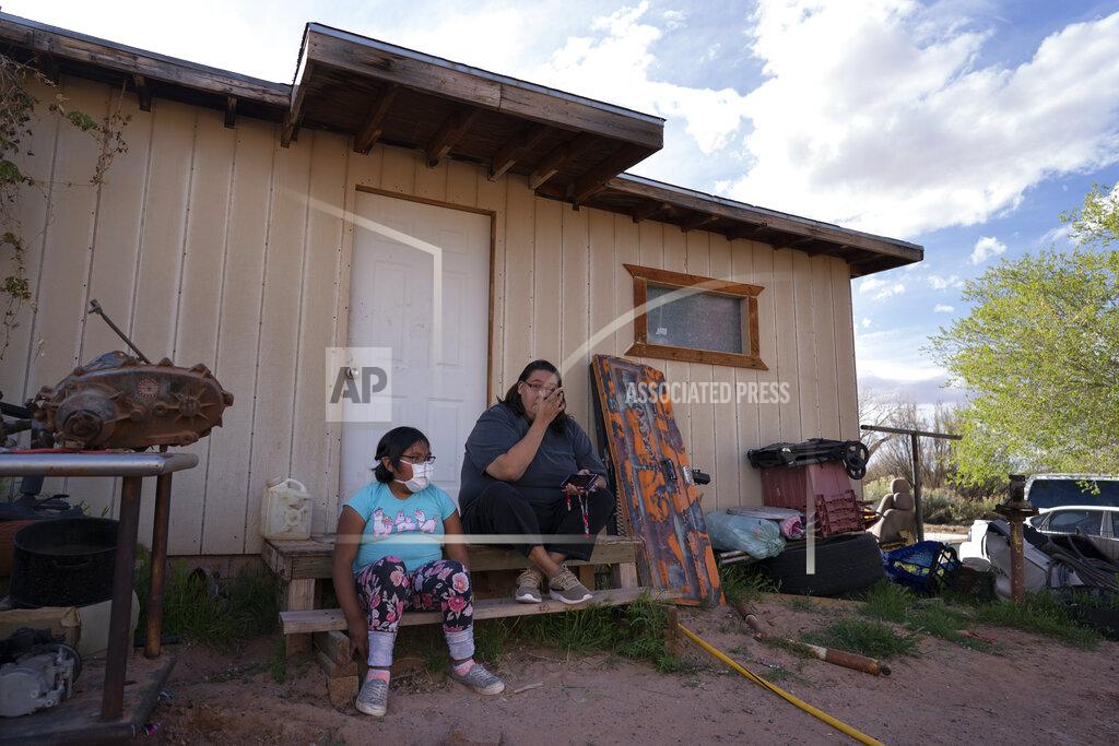 Carolyn Kaster Angelina Dinehdeal wipes tears from her eyes as she sits with her 8-year-old daughter, Annabelle, on the family's compound in Tuba City, Ariz., on April 20, 2020. The family has been devastated by COVID-19. The Navajo reservation has some of the highest rates of coronavirus in the country. If Navajos are susceptible to the virus' spread in part because they are so closely knit, that's also how many believe they will beat it. (AP Photo/Carolyn Kaster)