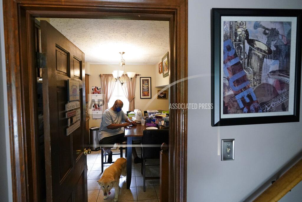 Darron Cummings Larry Brown sits at the kitchen table at his parents house, Thursday, Aug. 27, 2020, in Indianapolis. Recovering from COVID-19, Brown still has to stretch his hands and legs, which stiffen up frequently. (AP Photo/Darron Cummings)